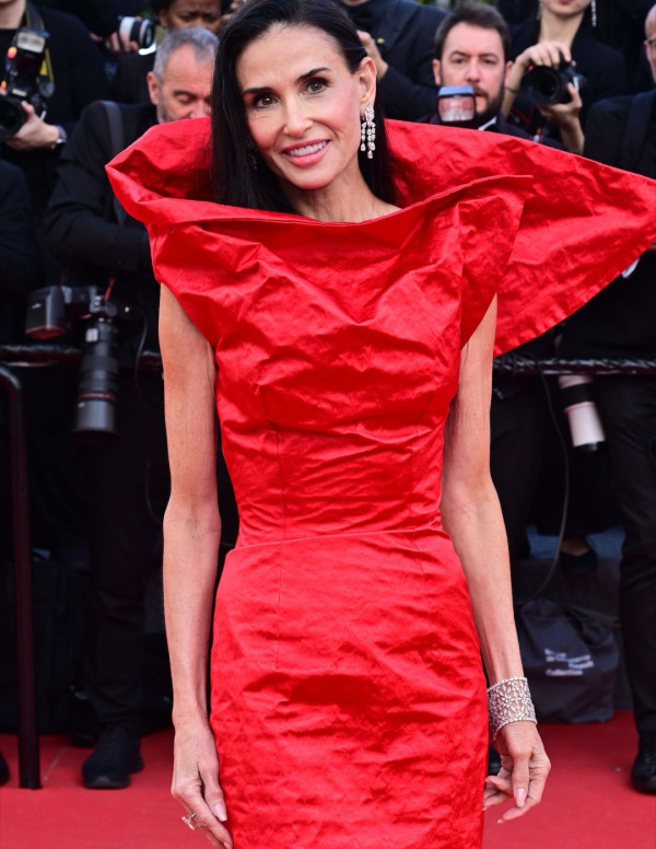 Demi Moore arrive à Cannes en rouge froissé et col très théâtral