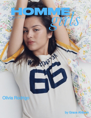 Olivia Rodrigo pose pour Homme Girls en tee-shirt oversize et bras levés